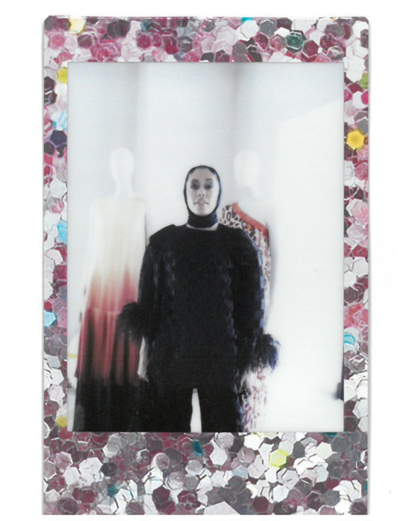 Junayaah in a black monochrome outfit poses against mannequins at the Dima Ayad showing.